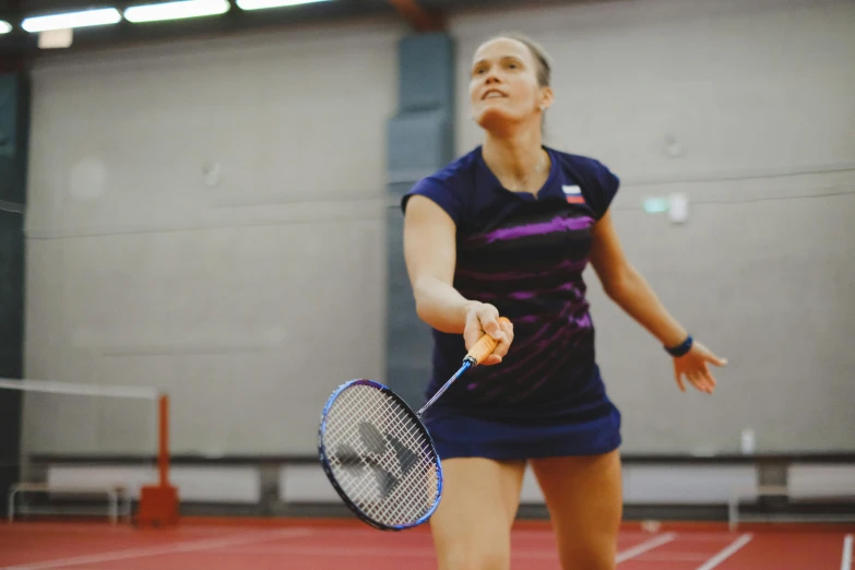 a woman in a blue shirt is holding a tennis racket