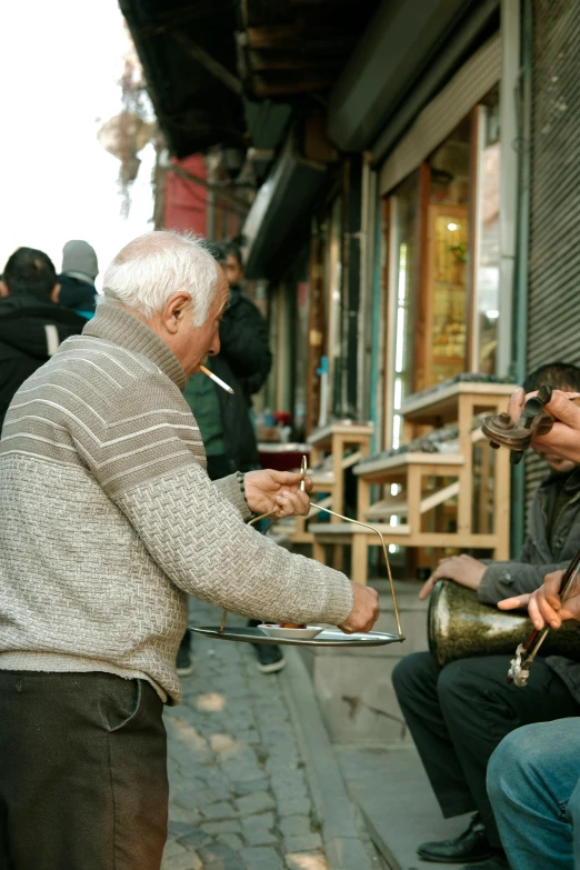 two men sitting on a sidewalk smoking, while one man sits down