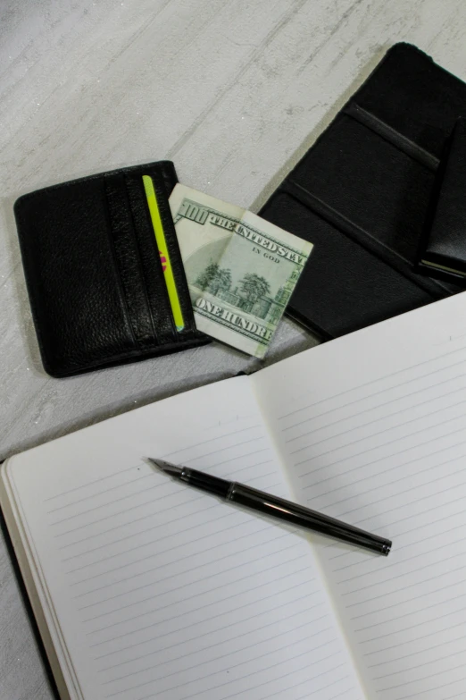 a wallet, pen and money on a white background