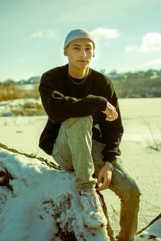 a young man sitting on top of a snow covered tree