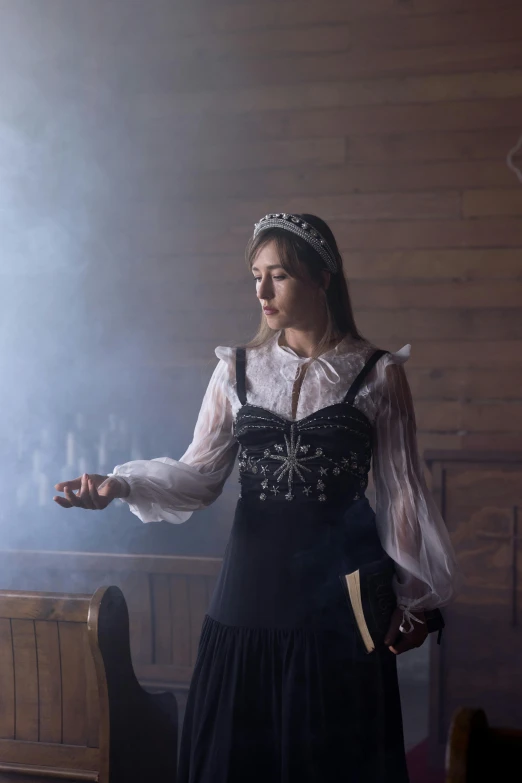 a woman dressed in period clothing stands beside a table