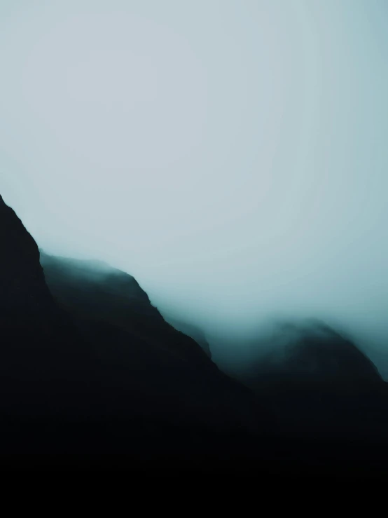 an airplane flying over a mountain covered in mist