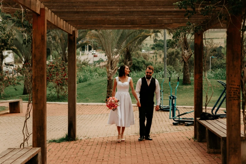 a bride and groom hold hands on a bench at the bottom of the path