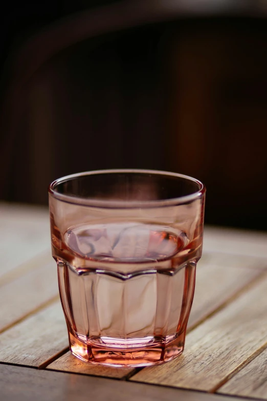 a glass filled with liquid on top of a wooden table