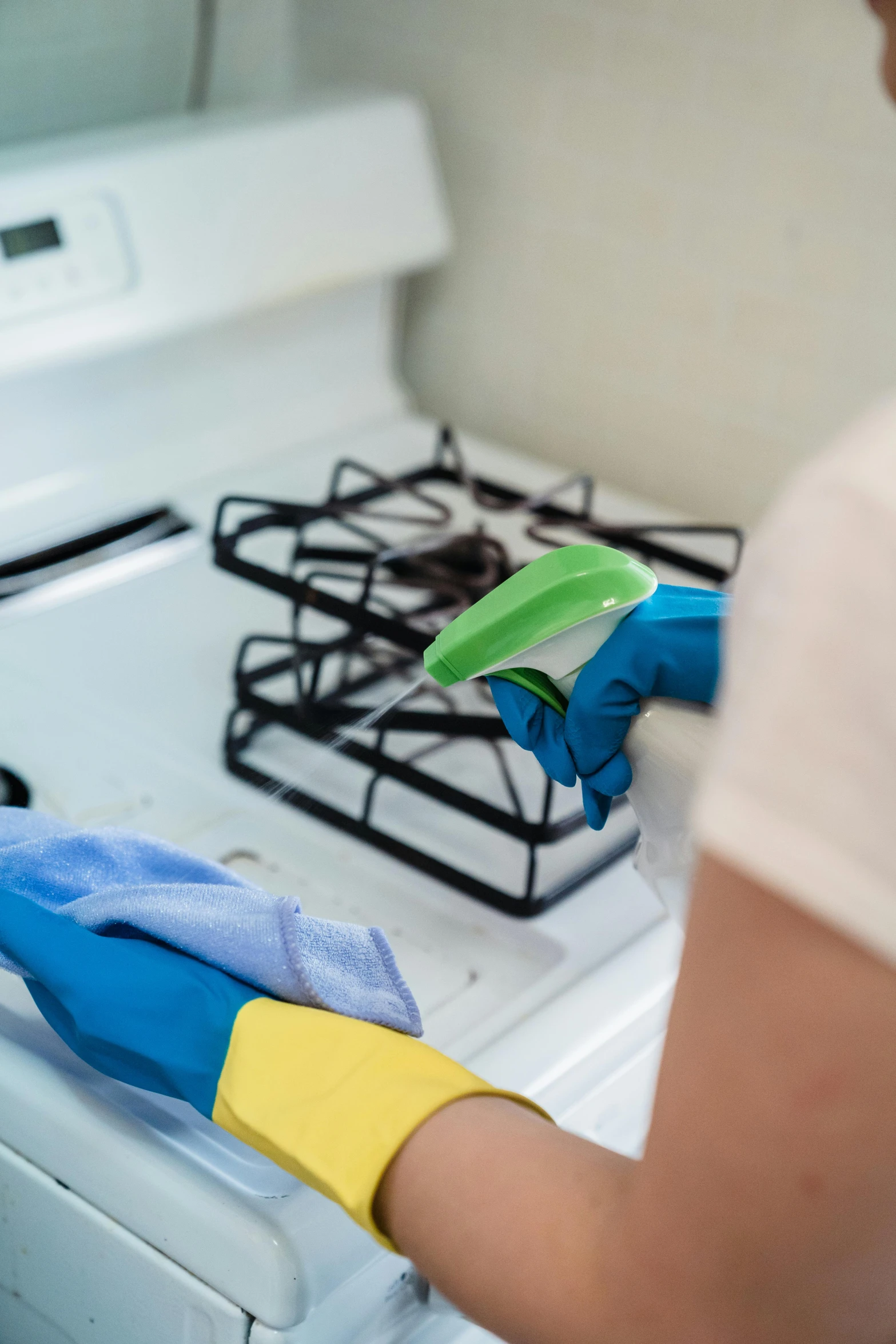 person in blue gloves cleaning the stove with rag