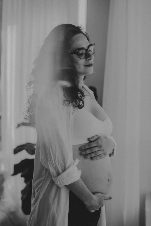 woman in white top and veil looking at baby bump