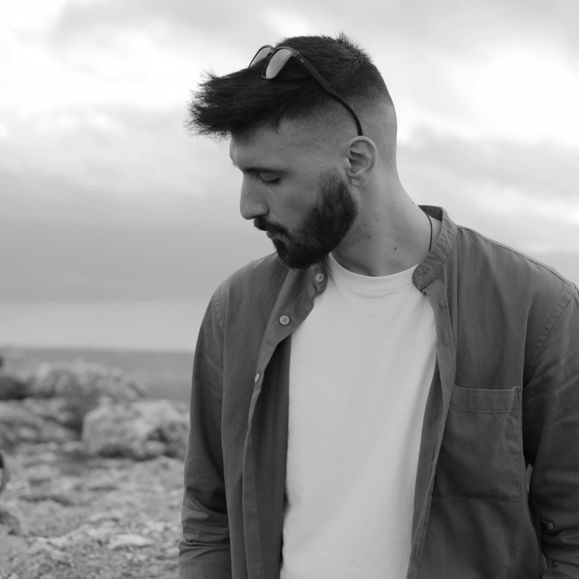 a bearded man with a white shirt and tie stands on the rocks