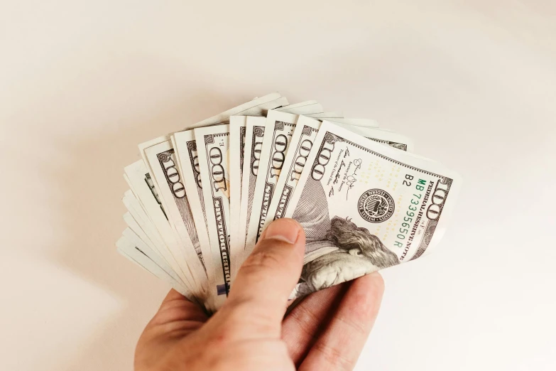 a person's hand holding several stacks of dollars