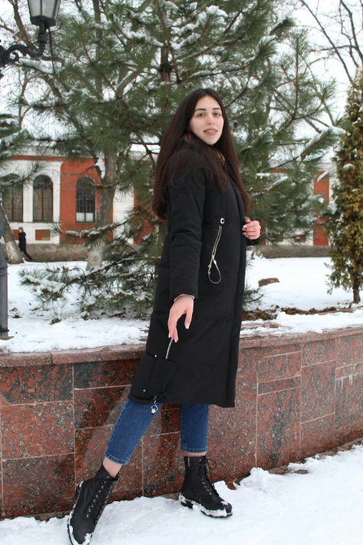 a woman standing outside in the snow wearing black