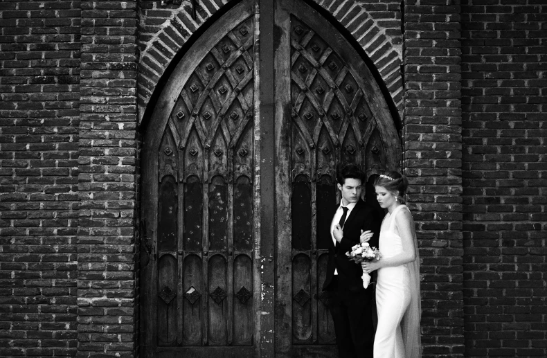 a bride and groom standing together in front of a door