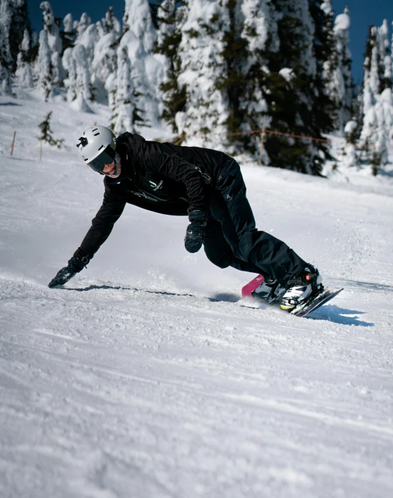 a snowboarder in a black jacket going down a slope