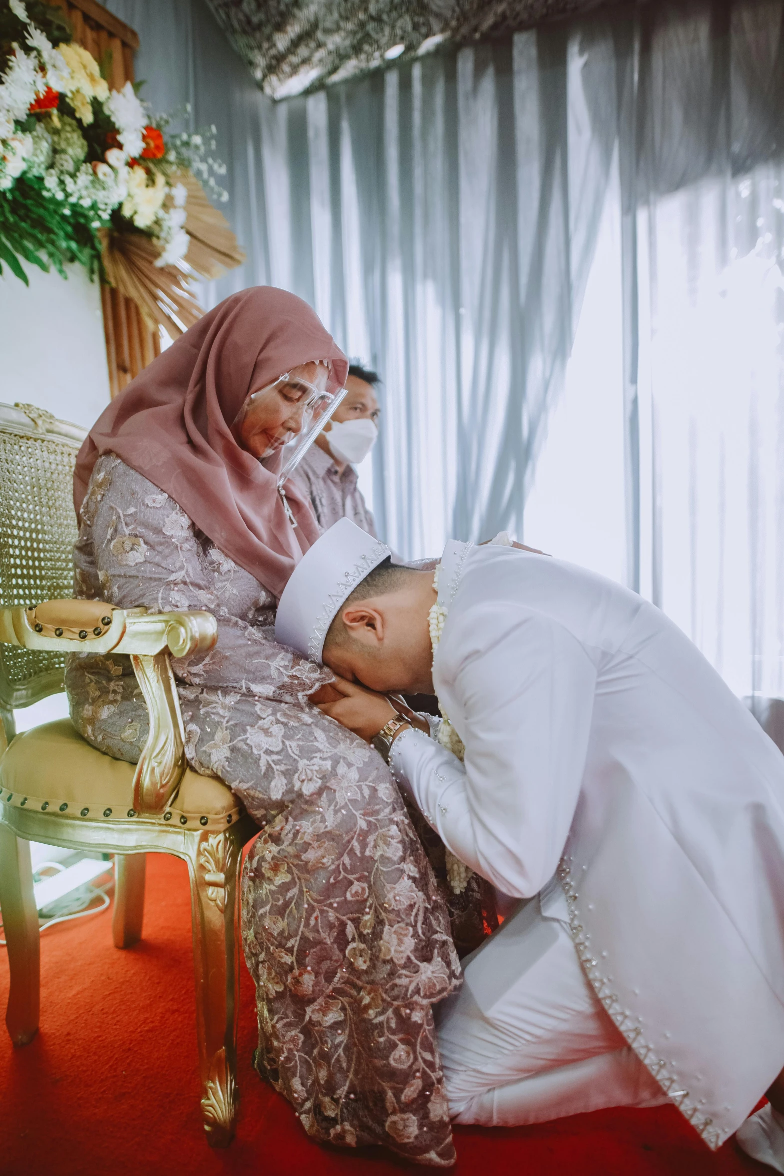 a man kissing the forehead of a women who is wearing a hijab