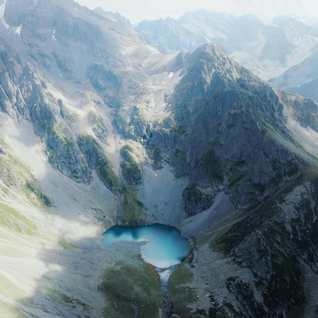 aerial view of a blue pond in the middle of mountains