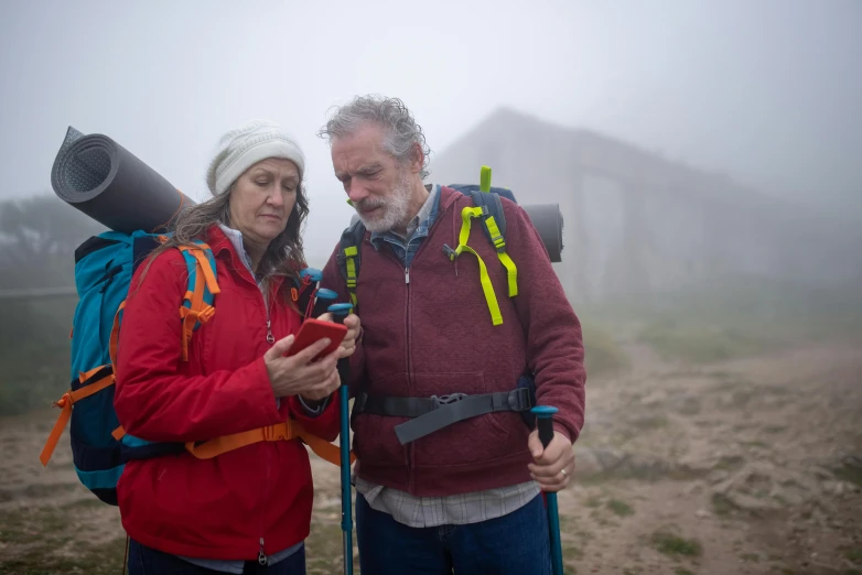 a man and woman in red jackets stand in the fog