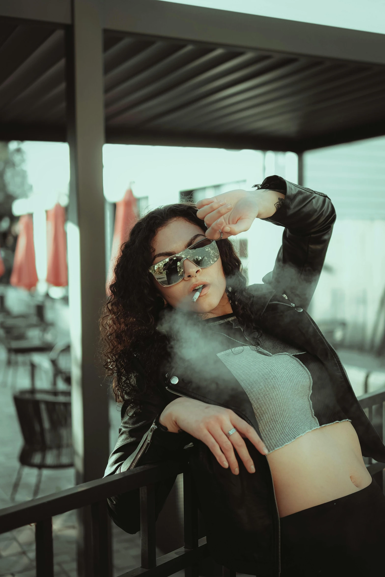 young woman smoking outside wearing sunglasses and smoke