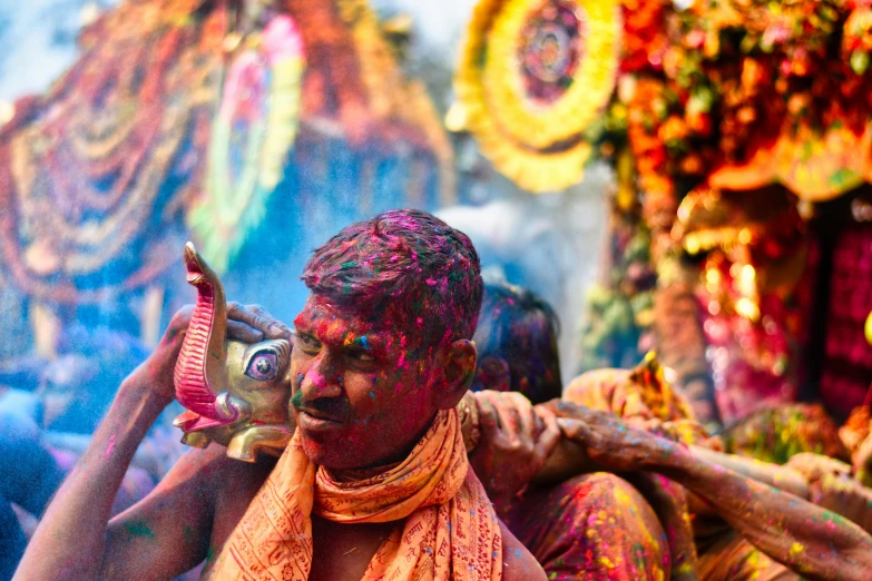 a man covered in colorful paint using a digital camera