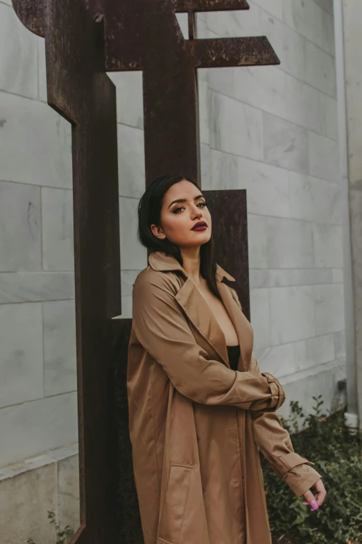 woman wearing a trench coat standing in front of a wall