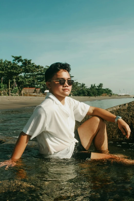 a man sits in shallow water by the shore