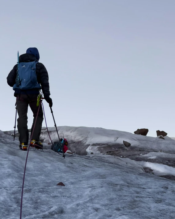 someone climbing up a snow covered mountain with ski poles