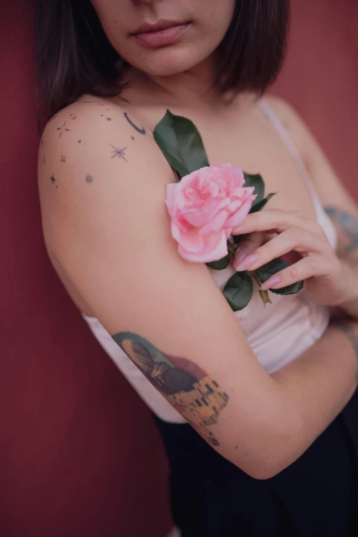 a woman in white tank top holding flower and pink roses