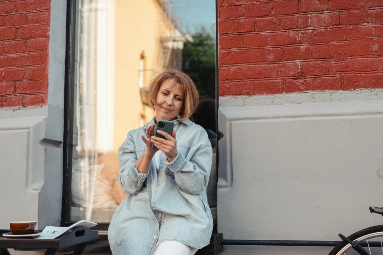 a woman is sitting outside looking at her cell phone