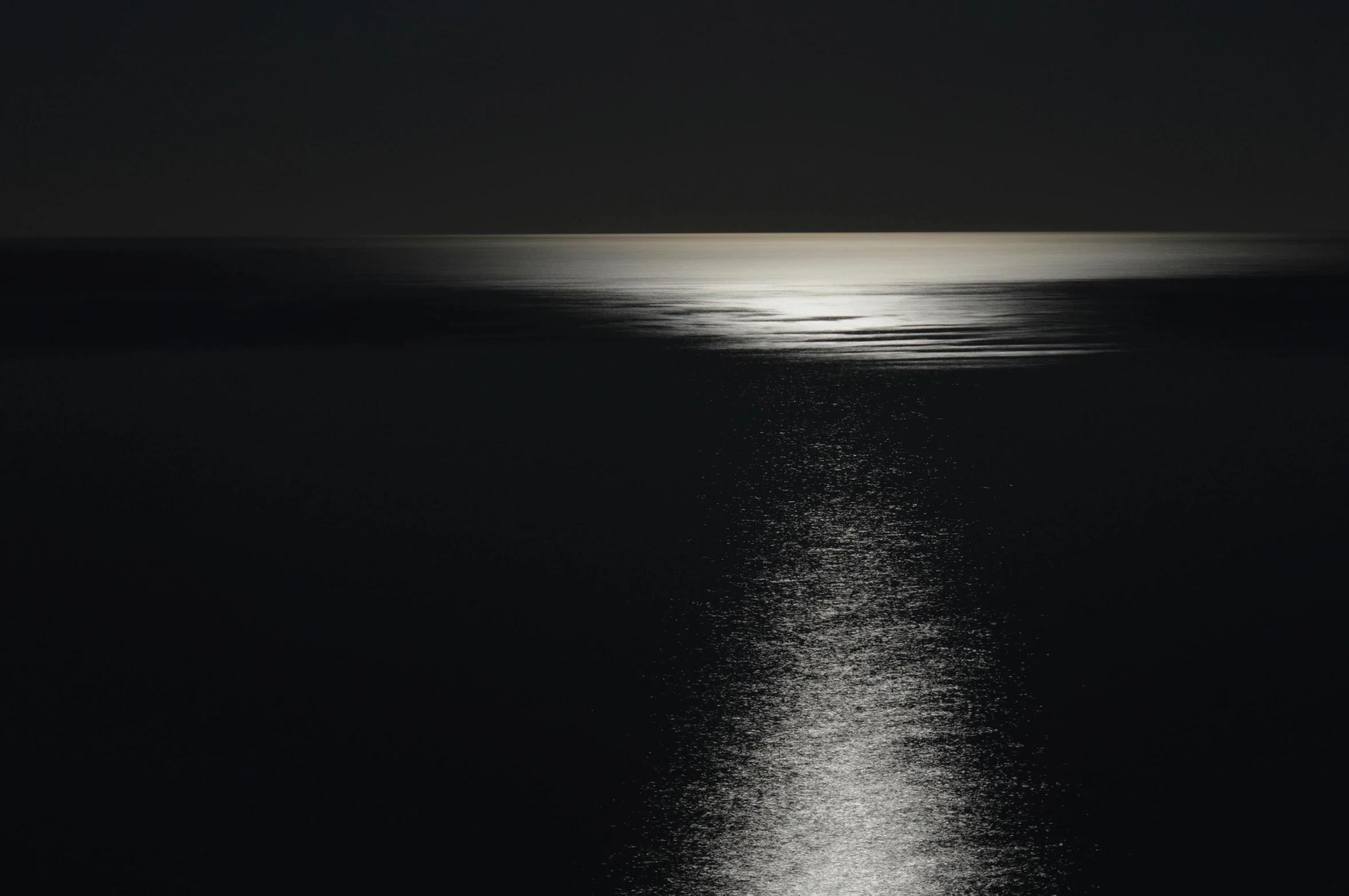 dark ocean view with bright light reflecting off the surface