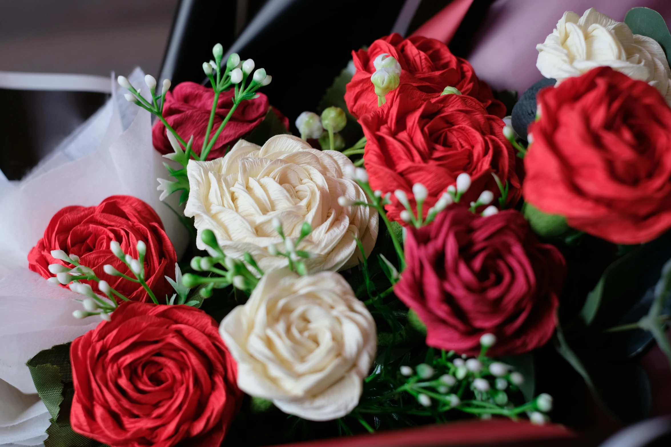 a bunch of red and white roses on a black table