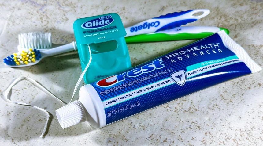 a toothbrush, toothpaste and razor blade sitting on a counter