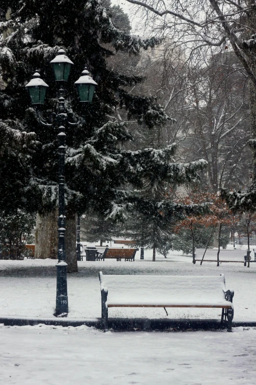 a bench sitting in the middle of a park covered in snow