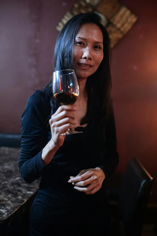 a woman in a dark dress with a glass of wine