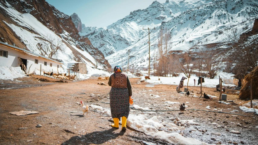 a person with a hat on is standing on a dirt lot near mountains