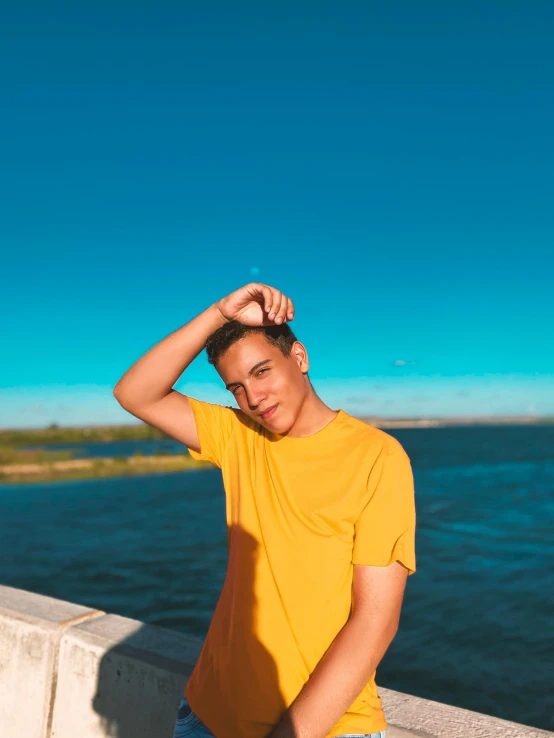 young man sitting on wall next to body of water