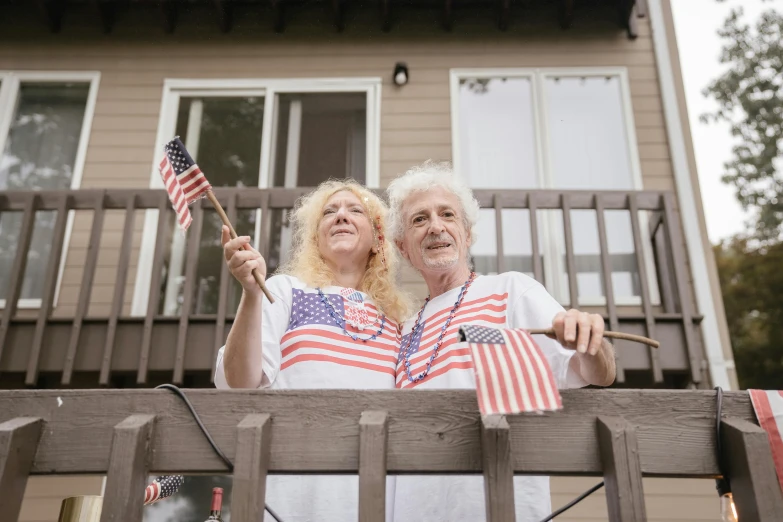 the couple are holding american flags outside of their house