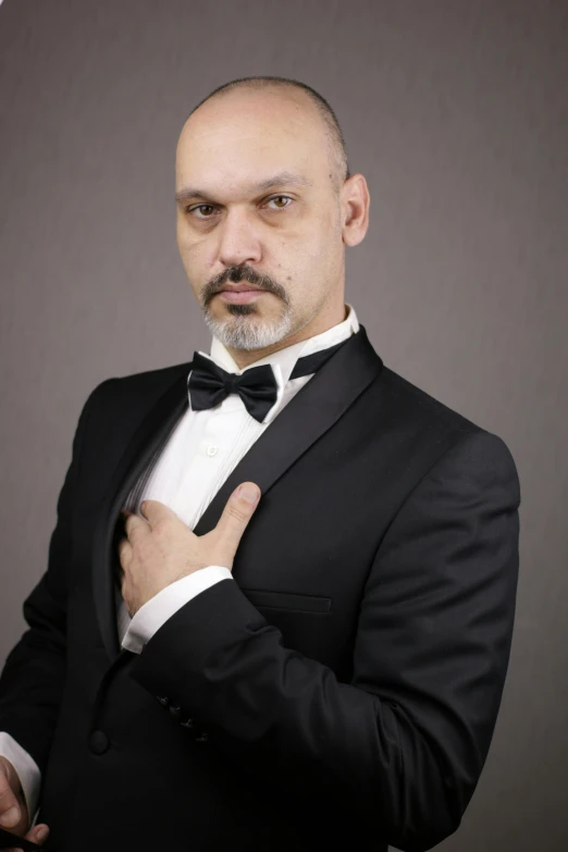 a man with a black jacket and white shirt is holding his bow tie