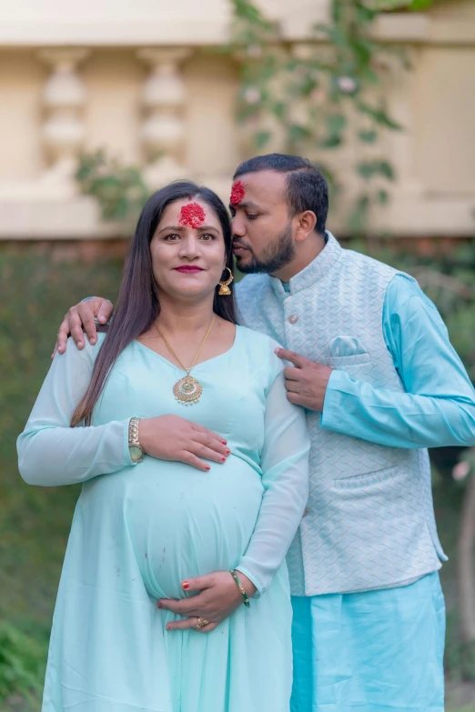 a pregnant woman with red flowers on her forehead and a man holding a girl in her lap