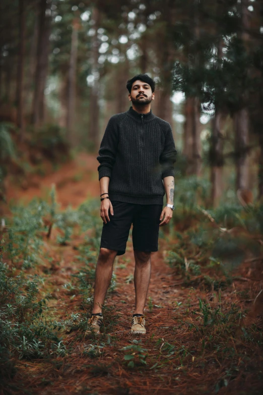 man in black sweater standing in a forest