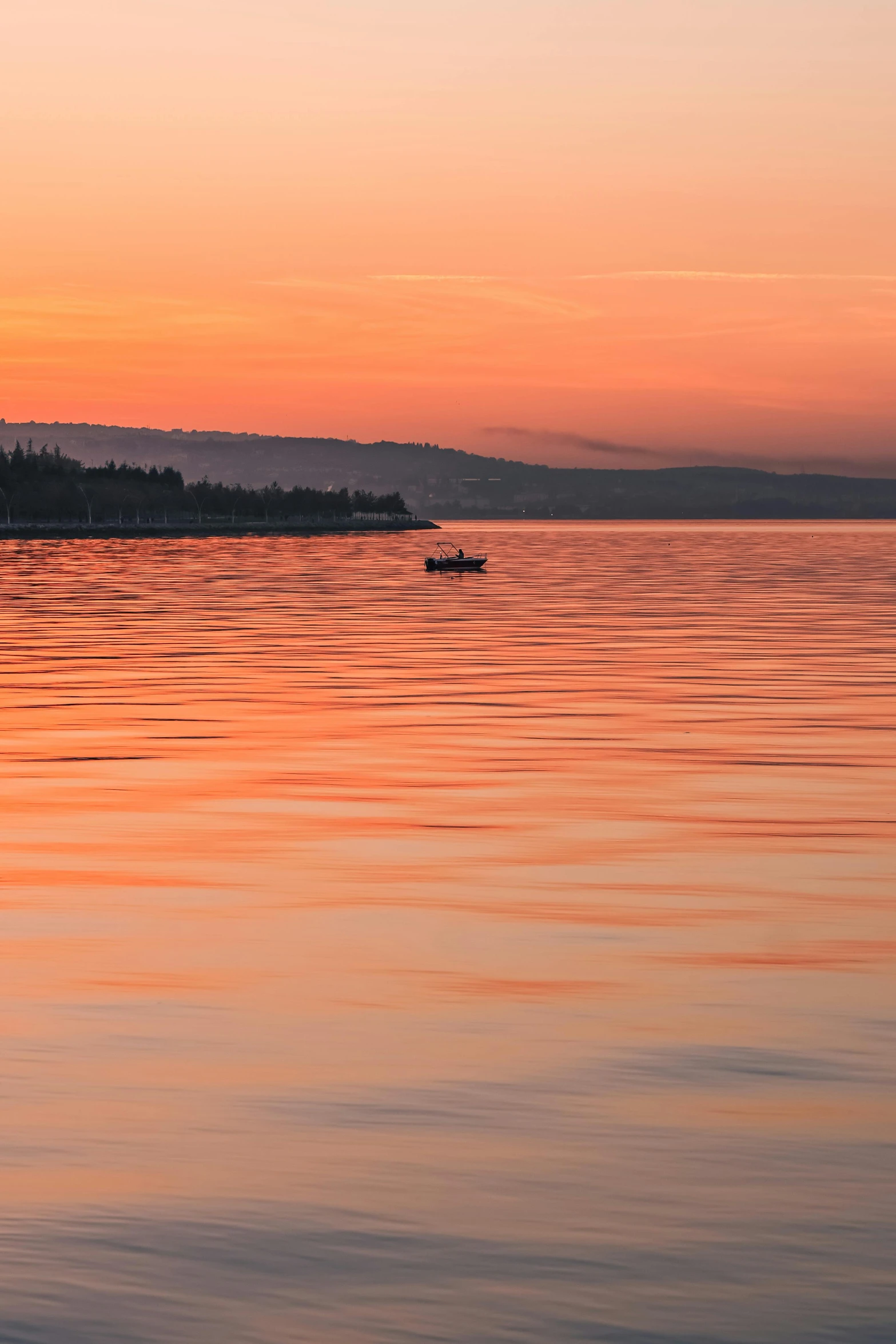 boat out on the ocean at sunset with hills in distance