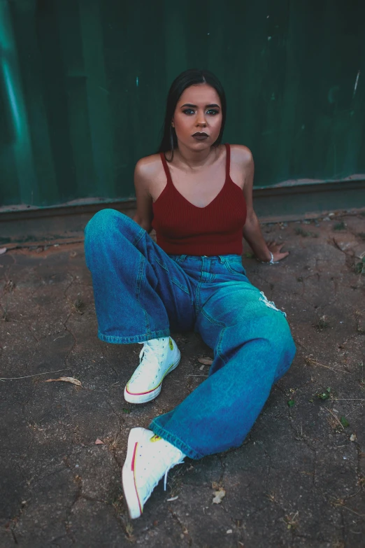 a woman in jeans sitting on the ground with her arms crossed