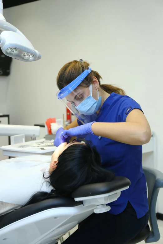 a female patient has an oxygen mask and a patient is having her temperature checked