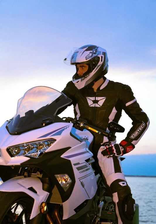 a man in a motorcycle uniform sitting on the back of a white bike