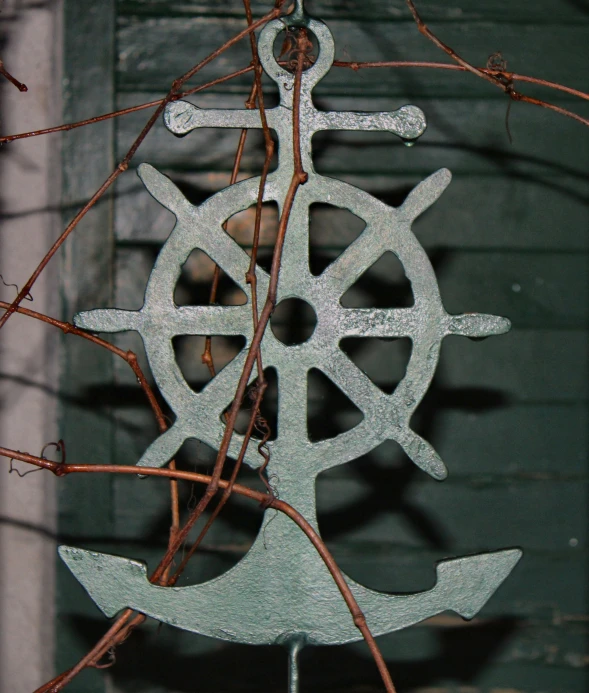 a piece of metal with a boat wheel on it and vines on the side