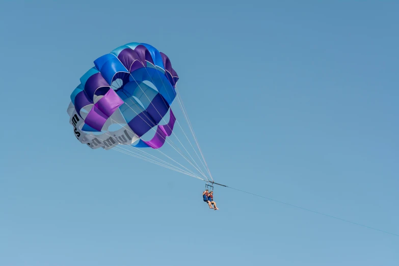 a person is in midair while holding onto a parachute