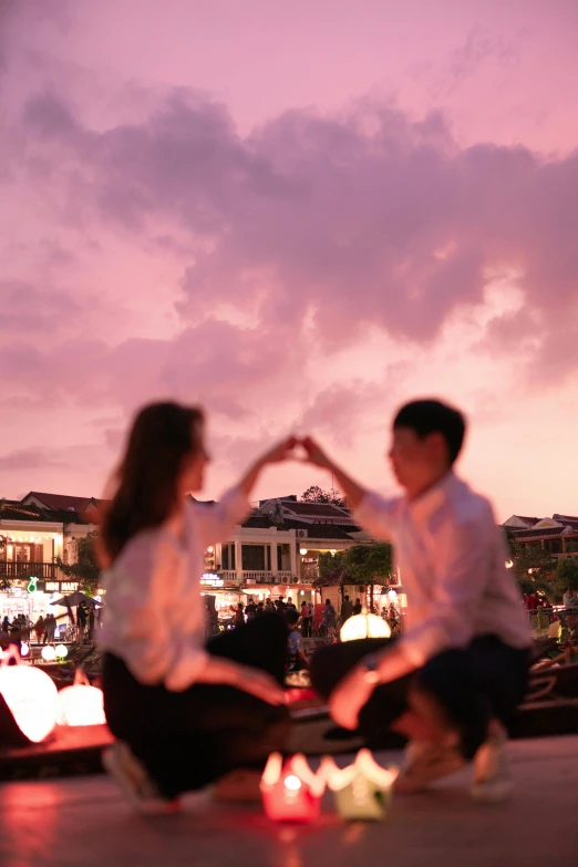 two people in dress clothing are sitting on a rooftop near the city