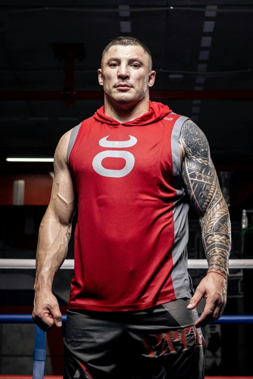 a tattooed man standing on top of a boxing ring