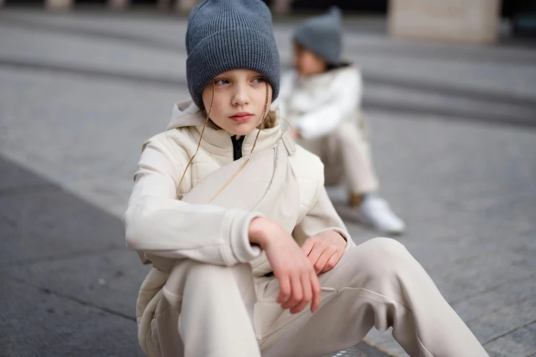 two children in winter outfits sitting on the ground