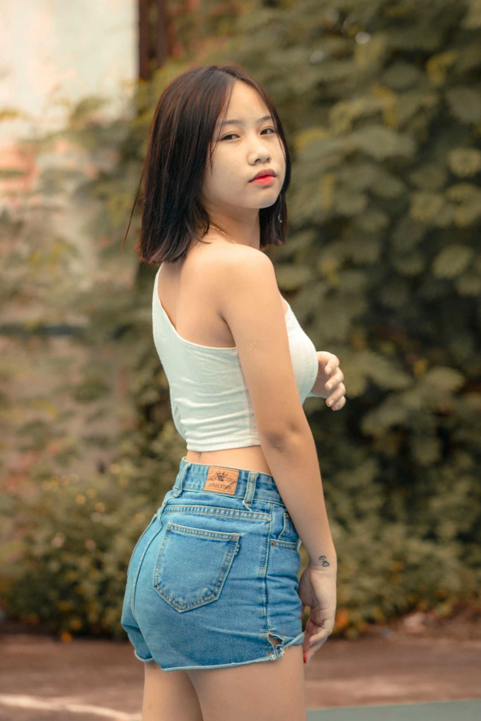 a woman wearing high waist denim shorts and crop tops