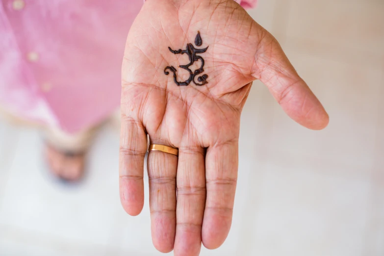 a woman's hand that has a black ink sign of the word om in it