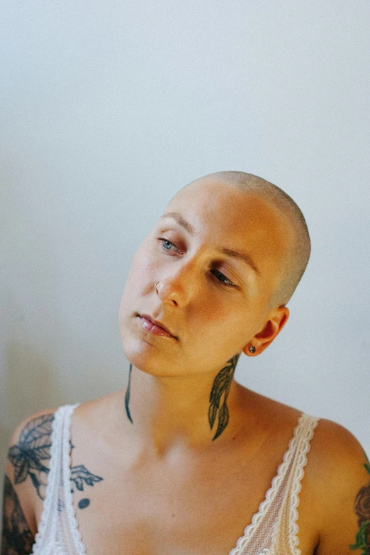 tattooed woman in white tank top with her face slightly closed