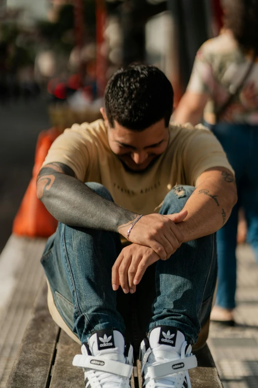 a man wearing jeans sitting on a bench