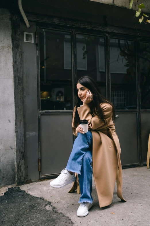 a woman with long hair and white sneakers is sitting outside